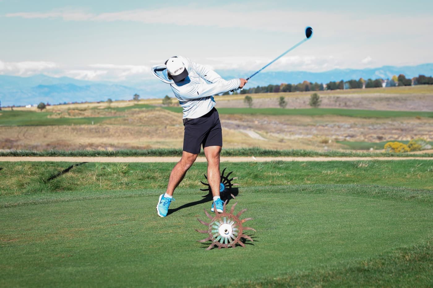 A player tees off with the Front Range on the horizon